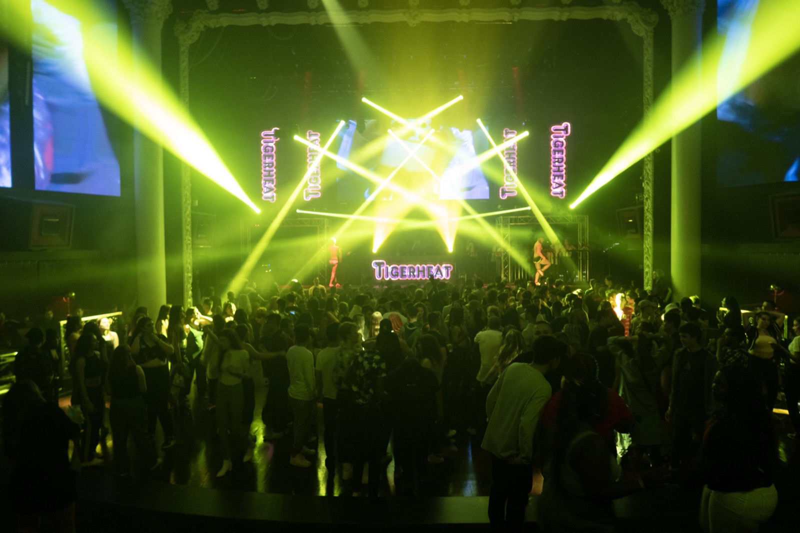 A nightclub dance floor bathed in colored laser light.