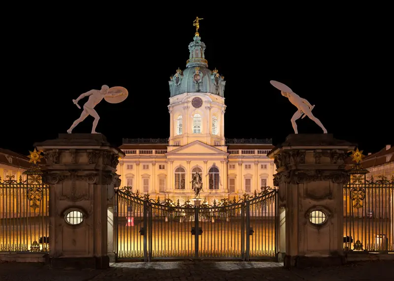 Schloss Charlottenburg bei Nacht in Berlin, beleuchtete Fassade gegen den dunklen Himmel.