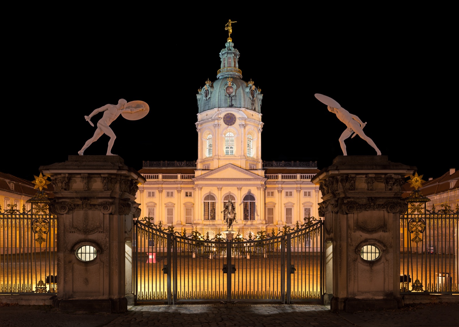 Schloss Charlottenburg bei Nacht in Berlin, beleuchtete Fassade gegen den dunklen Himmel.
